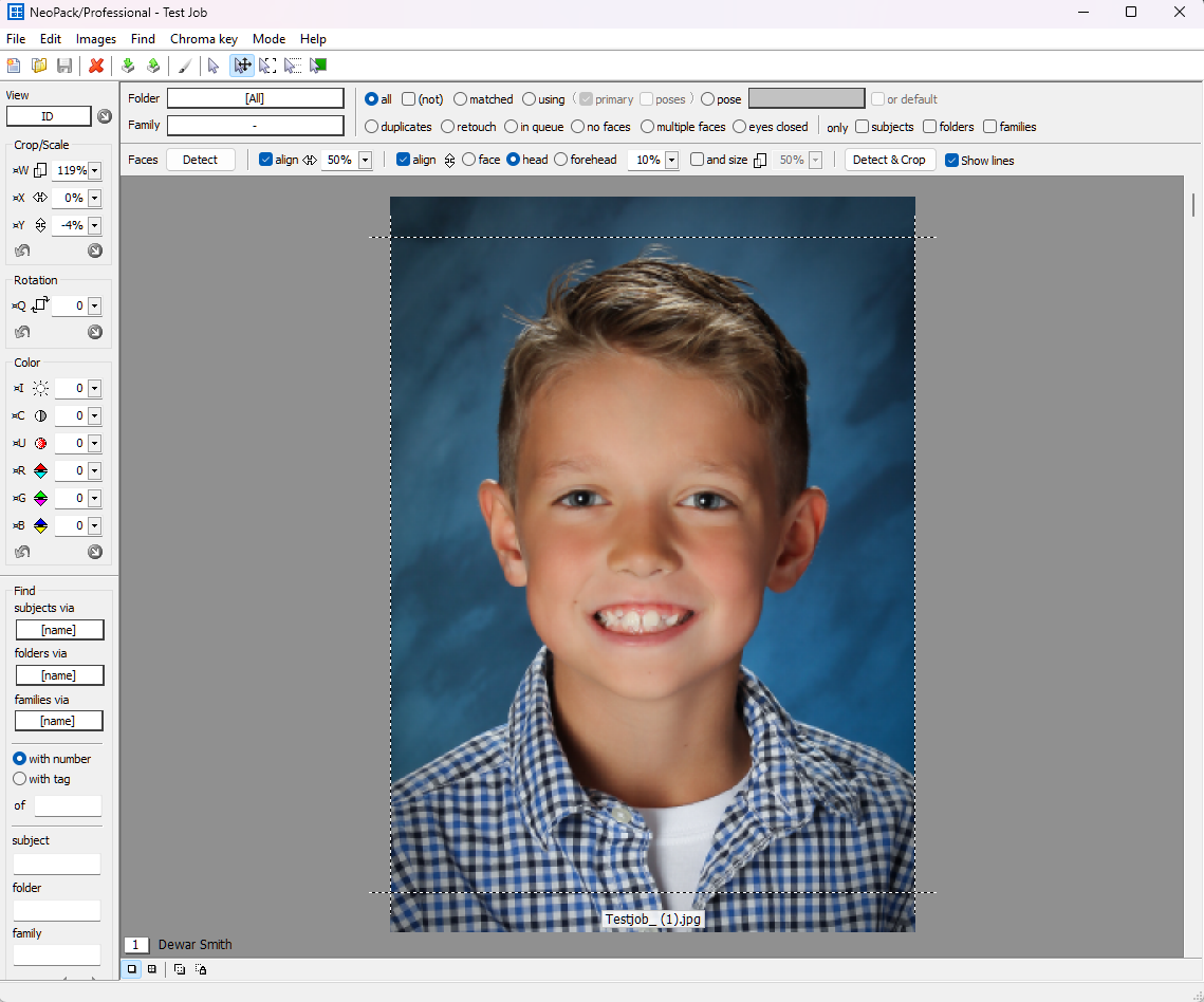 A smiling boy with short hair wearing a checkered shirt poses for a photo.