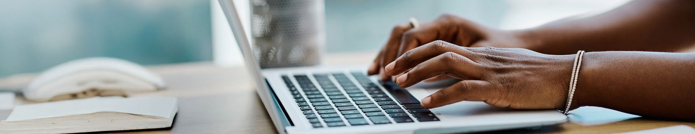 Banner showing QuestUP e-Assessment system on a blue left panel, the QuestUP Workshop logo in the centre, and hands typing on a laptop on the right