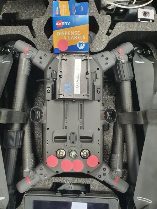 Underside of a DJI M300 with all four downward vision sensors covered by labels